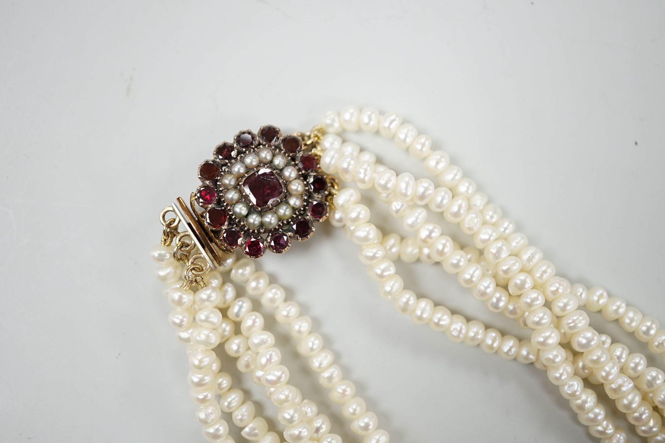 A cultured baroque pearl torsade choker necklace, with early yellow metal garnet and split pearl set clasp, 38cm.